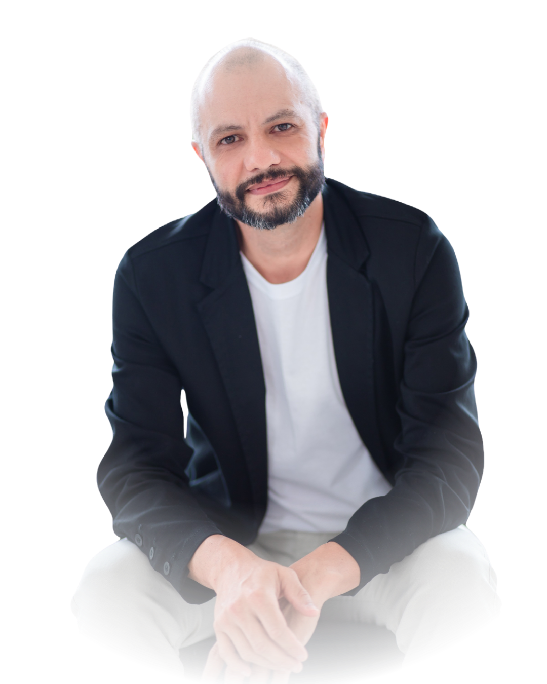 Lubben sentado, de blazer preto e camiseta branca, sorrindo