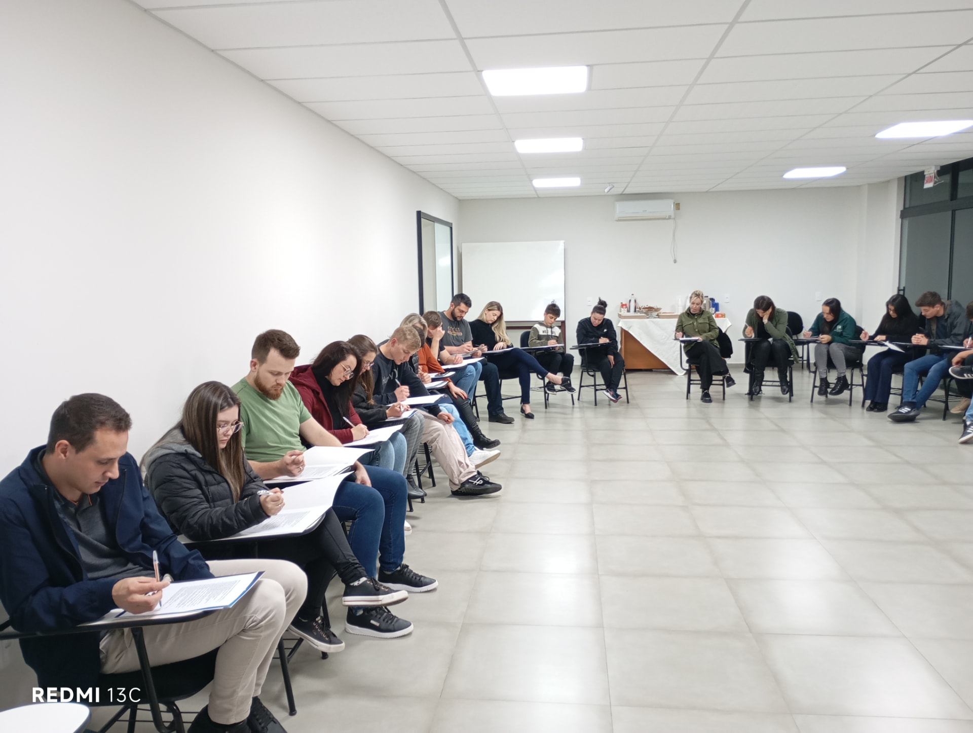 Participantes realizando atividade escrita em sala de treinamento